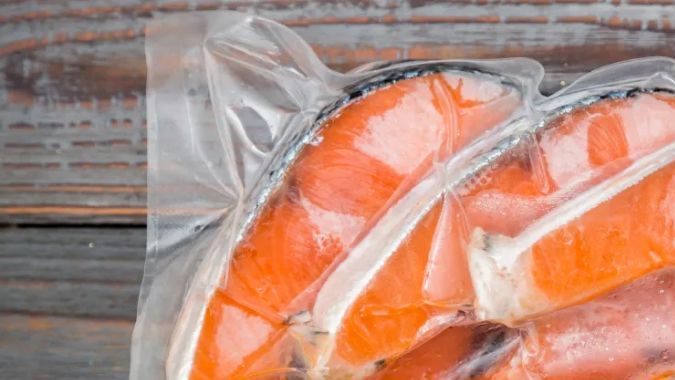 Bolsa de vacío con pescado sobre un fondo de madera rustico