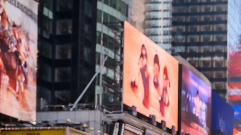Multitud de turistas caminando por Times Square en Manhattan rodeados de pantallas gigantes y rascacielos