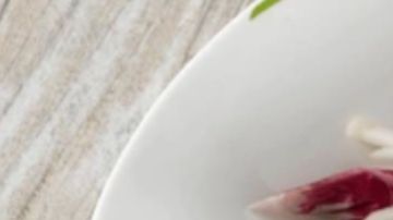 Ensalada detox de láminas finas de manzana verde y cebolla roja, aderezada con limón y pimienta negra en un bol de cerámica blanca, estilo fotografía culinaria profesional.