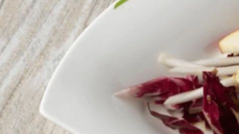 Ensalada detox de láminas finas de manzana verde y cebolla roja, aderezada con limón y pimienta negra en un bol de cerámica blanca, estilo fotografía culinaria profesional.
