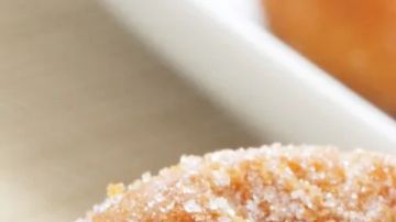 Plato de cerámica blanca con varios roscos de Semana Santa fritos, cubiertos de una capa generosa de azúcar y almíbar. Tienen un tono dorado y se aprecian las motas del anís.