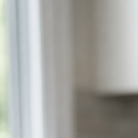 Fotografía editorial hiperrealista de una mujer latina de 40 a 55 años sentada en la mesa de una cocina moderna en Estados Unidos, observando un frasco de medicamento genérico y varias pastillas sobre la mesa con expresión pensativa.