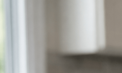 Fotografía editorial hiperrealista de una mujer latina de 40 a 55 años sentada en la mesa de una cocina moderna en Estados Unidos, observando un frasco de medicamento genérico y varias pastillas sobre la mesa con expresión pensativa.