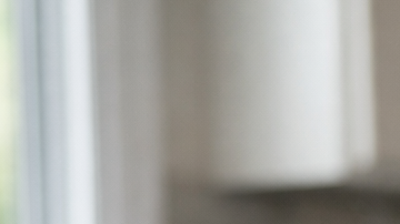 Fotografía editorial hiperrealista de una mujer latina de 40 a 55 años sentada en la mesa de una cocina moderna en Estados Unidos, observando un frasco de medicamento genérico y varias pastillas sobre la mesa con expresión pensativa.