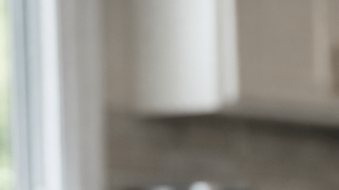 Fotografía editorial hiperrealista de una mujer latina de 40 a 55 años sentada en la mesa de una cocina moderna en Estados Unidos, observando un frasco de medicamento genérico y varias pastillas sobre la mesa con expresión pensativa.