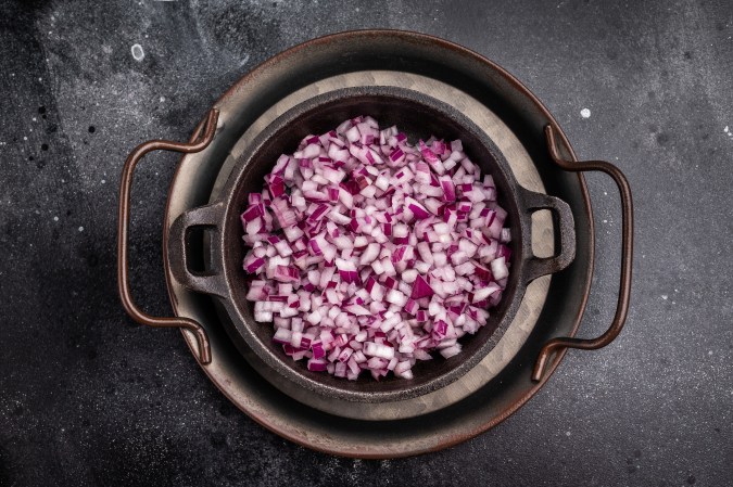 Cebolla morada cortada en un caldero de hierro.