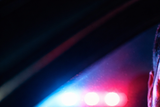Joven latino durante un control policial en EE.UU. con luces de patrulla
