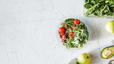 Mujer rodeada de alimentos ricos en proteínas y minerales que fortalecen el cabello,