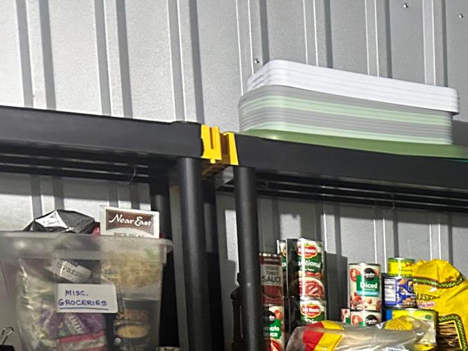 Storage shelves filled with various food items, including canned goods, boxes of cereal, and pasta, organized in a storage area.