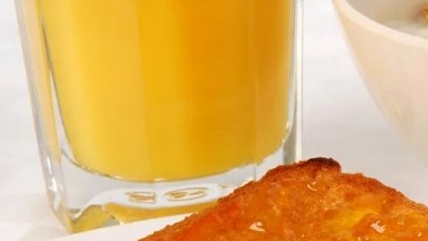Desayuno tradicional con huevos revueltos, pa tostado, jugo de naranja y café con una figura de dos riñones el lado derecho.