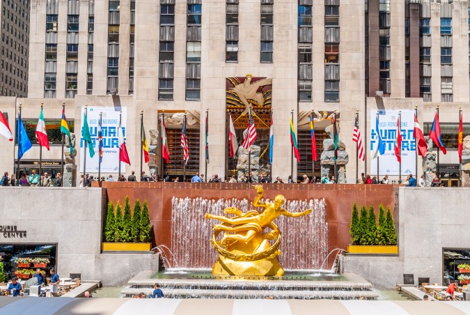 La estatua dorada de Prometeo en la plaza del Rockefeller Center rodeada por banderas internacionales, sede del Telemundo Fan Village durante el Mundial 2026.