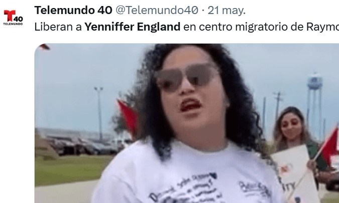 A woman speaking at a rally outside a migration center in Raymondville, Texas, with supporters holding signs and flags in the background.