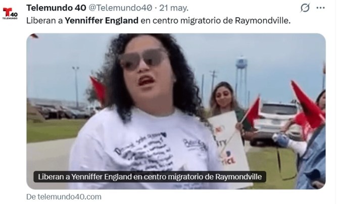 A woman speaking at a rally outside a migration center in Raymondville, Texas, with supporters holding signs and flags in the background.