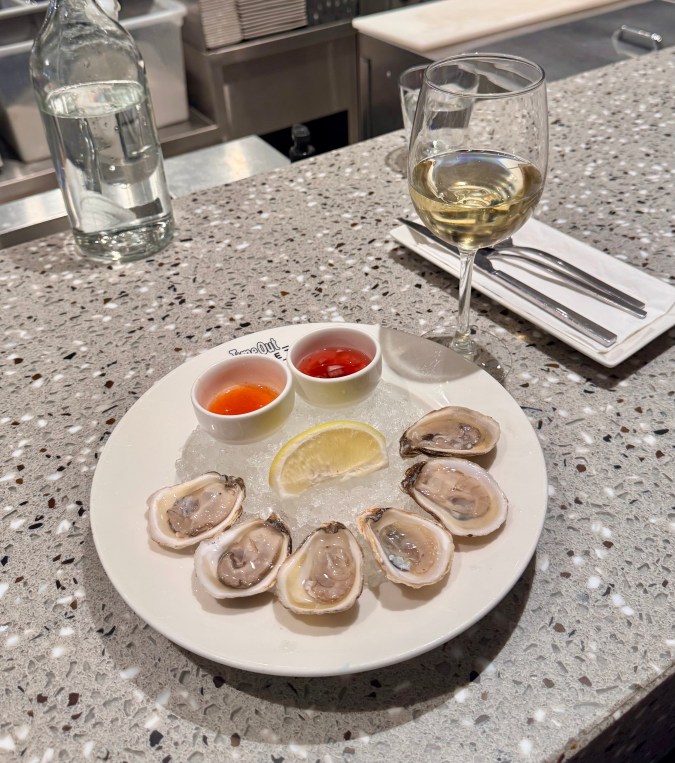 Plato de ostras con una copa de vino blanco en el Time Out Market de Montreal