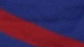 Un hombre pasa junto a una enorme bandera cubana mientras un grupo de cubanos se reúne para sostener pancartas y ondear banderas horas después de que los fiscales federales anunciaran cargos contra el expresidente cubano Raúl Castro.