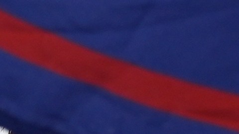 Un hombre pasa junto a una enorme bandera cubana mientras un grupo de cubanos se reúne para sostener pancartas y ondear banderas horas después de que los fiscales federales anunciaran cargos contra el expresidente cubano Raúl Castro.