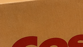 Pastel personalizado de Costco junto a bandejas de comida para fiestas y una caja de entrega a domicilio, en una cocina.