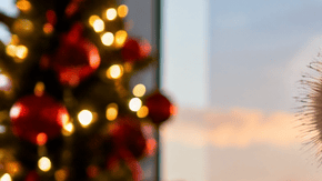 Viajera con valija en un aeropuerto decorado para las fiestas frente a un avión al atardecer