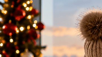 Viajera con valija en un aeropuerto decorado para las fiestas frente a un avión al atardecer