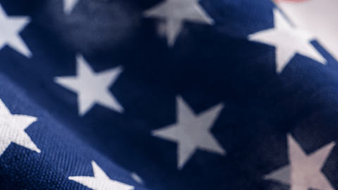 Formulario de USCIS junto a un permiso de trabajo, un pasaporte y la bandera de Estados Unidos